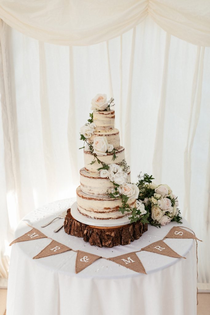 naked wedding cake with fresh flowers by holly & ivy flowers